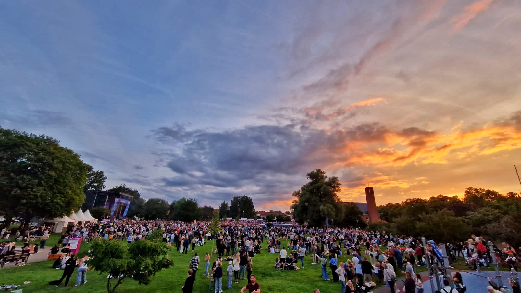 Sommarkväll, solnedgång i Vasaparken med mycket människor och en stor scen.