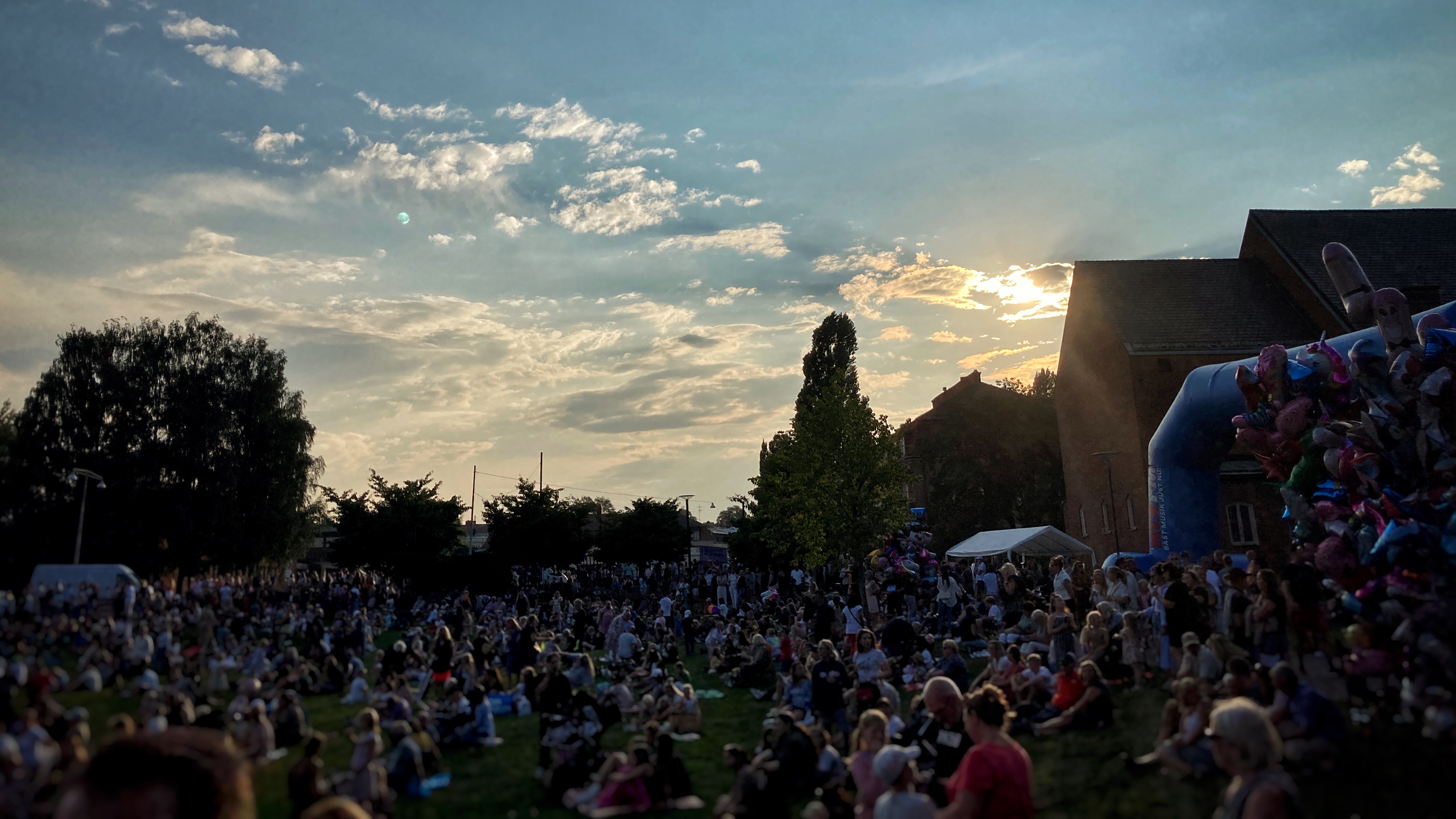Sommarkväll, solnedgång i Vasaparken där massor människor sitter eller står och tittar på konsert,